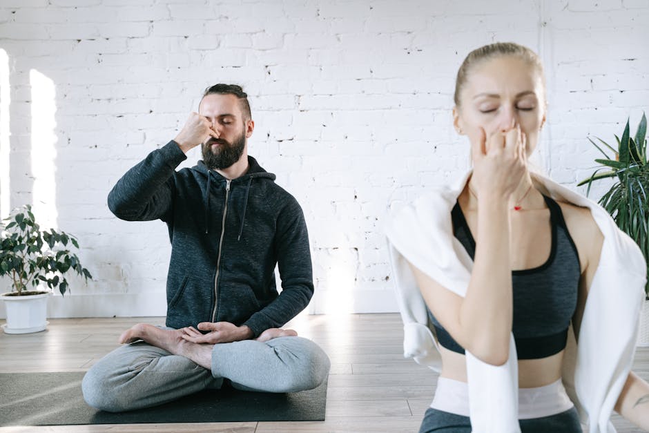 Woman in a calm yoga pose inside a brightly lit, peaceful room with plants.